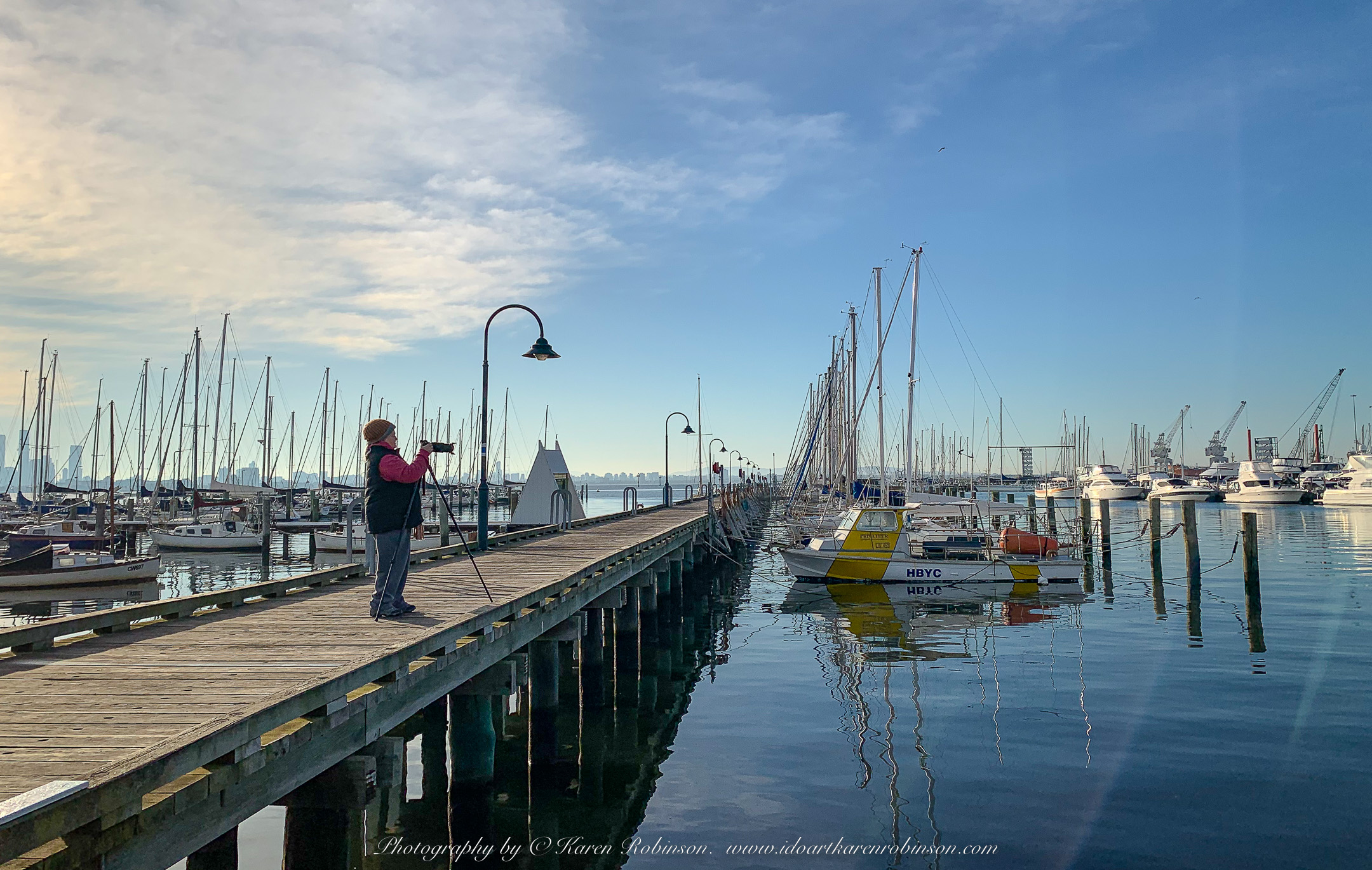 Williamstown, Victoria - Australia 'Views from Ferguson Street Pier' Photographed by ©Mark Robinson June 2022 Comment: Photograph featuring views across Port Phillip Bay and anchored boats and yachts and Karen Robinson Photographing scene.